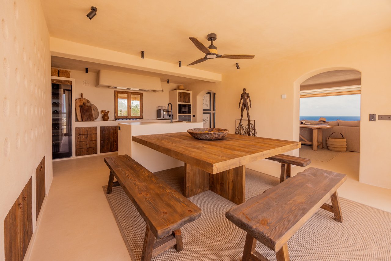 Comedor de la cocina con mesa de madera, bancos y ventilador de techo