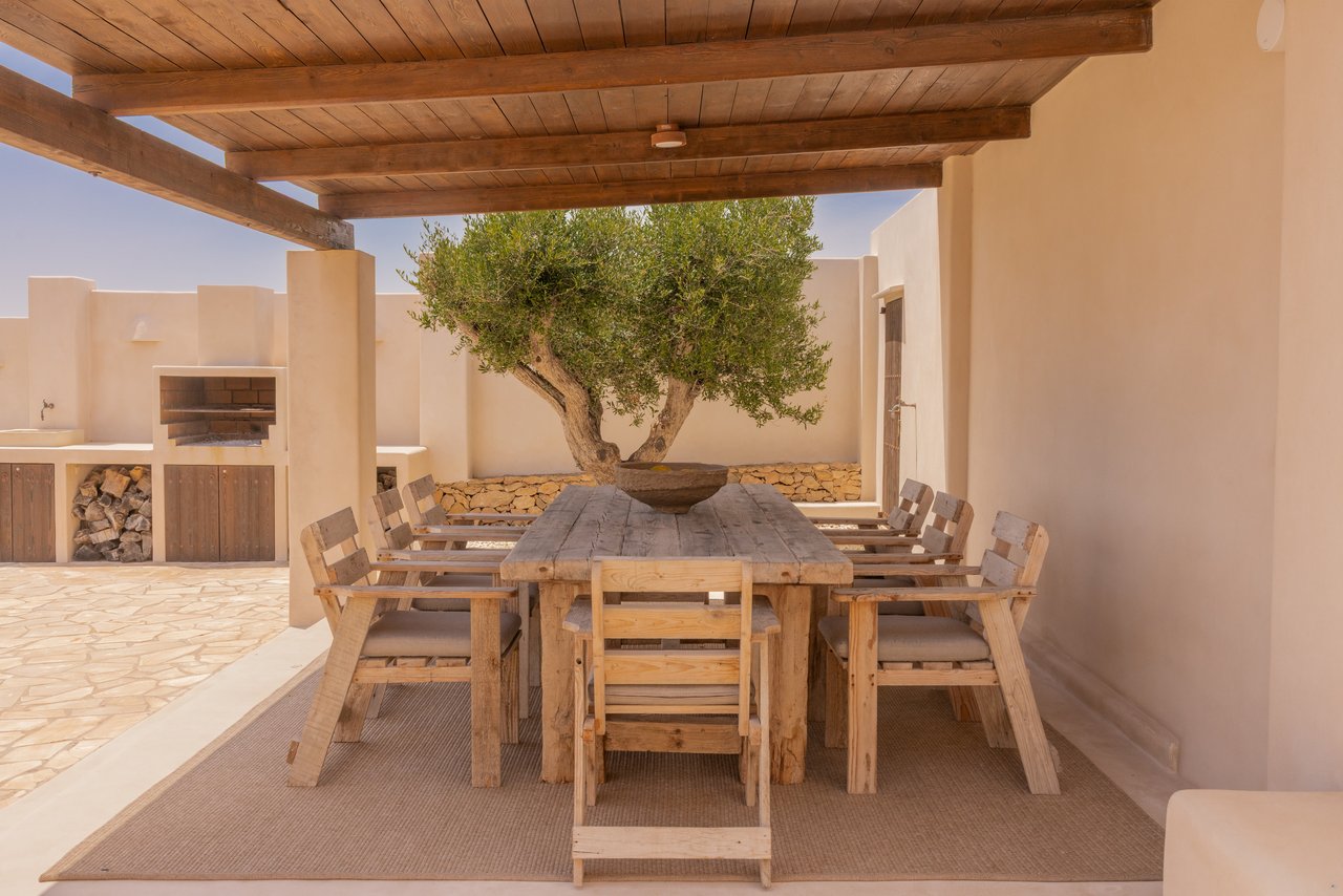 Comedor exterior bajo la pérgola con el olivo en el centro